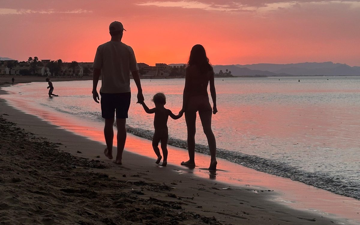 Elena paseando con su familia por la playa al atardecer